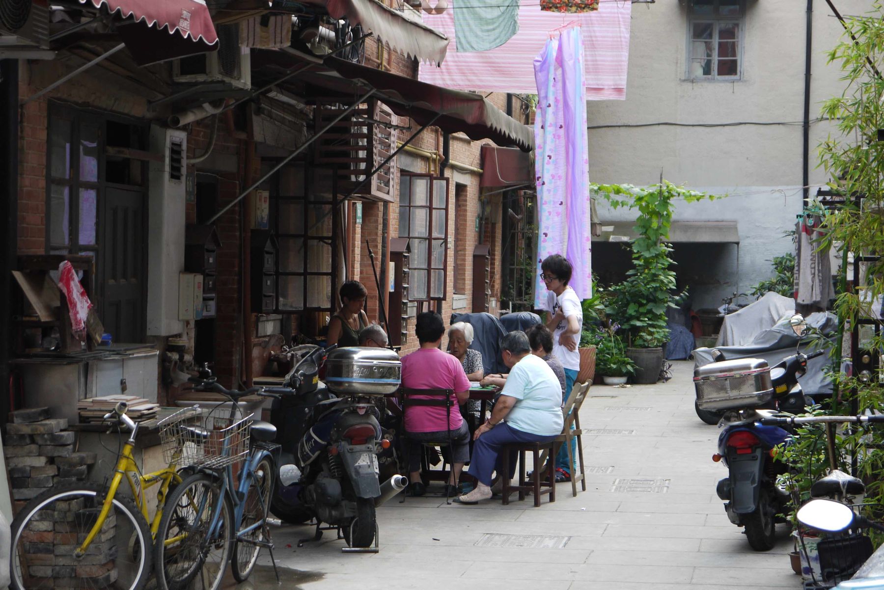 The lane as living room — cards, scooters, laundry.